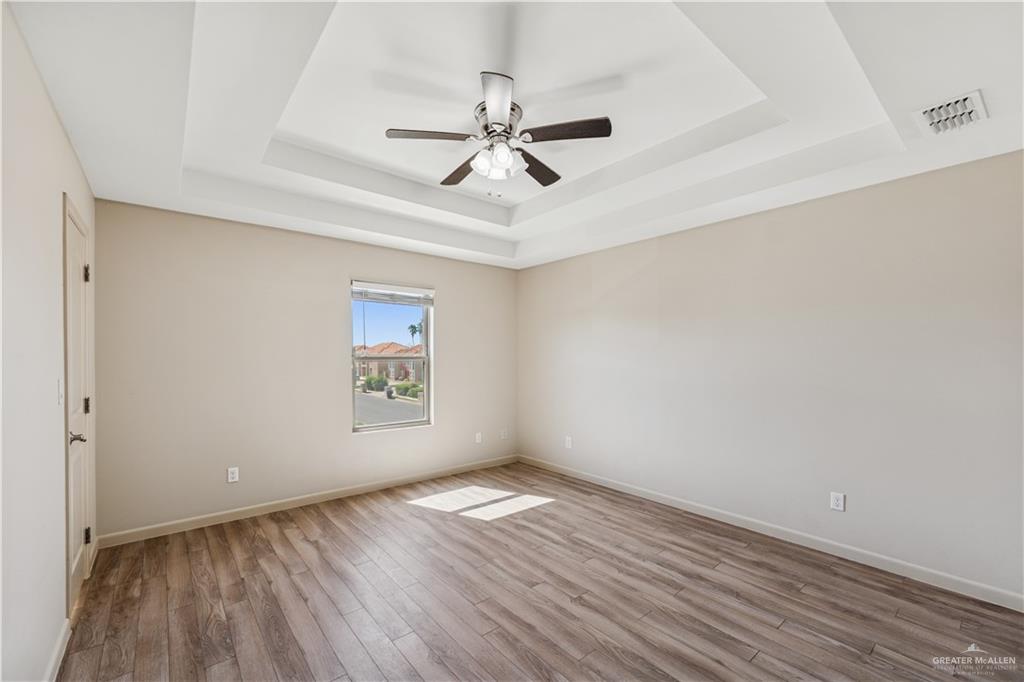 1201 East Olympia Avenue, Unit 2 McAllen, TX 78503 - Photo 14 of 15 an empty room with wooden floor ceiling fan and windows
