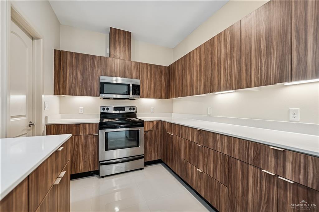 1201 East Olympia Avenue, Unit 2 McAllen, TX 78503 - Photo 6 of 15 a kitchen with granite countertop wooden cabinets a stove and a oven