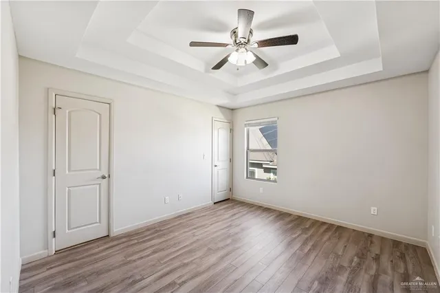 an empty room with wooden floor chandelier fan and windows