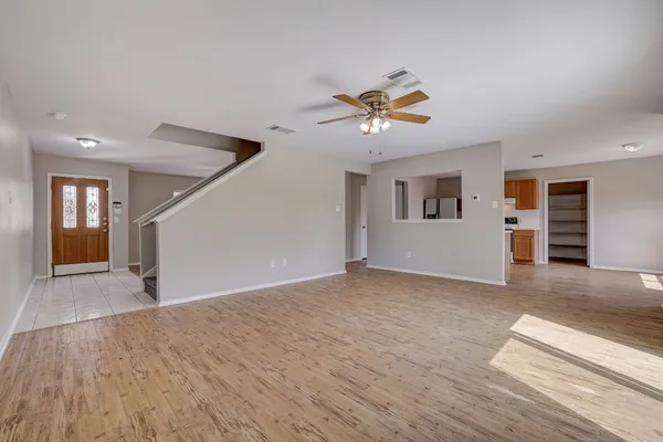 a view of empty room with wooden floor and ceiling fan
