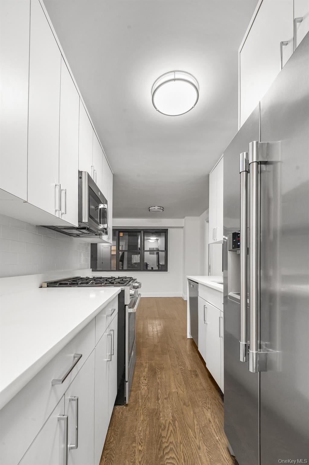 19-50 80th Street, Unit 1 Queens, NY 11370 - Photo 4 of 20 a kitchen with stainless steel appliances granite countertop a refrigerator sink and cabinets