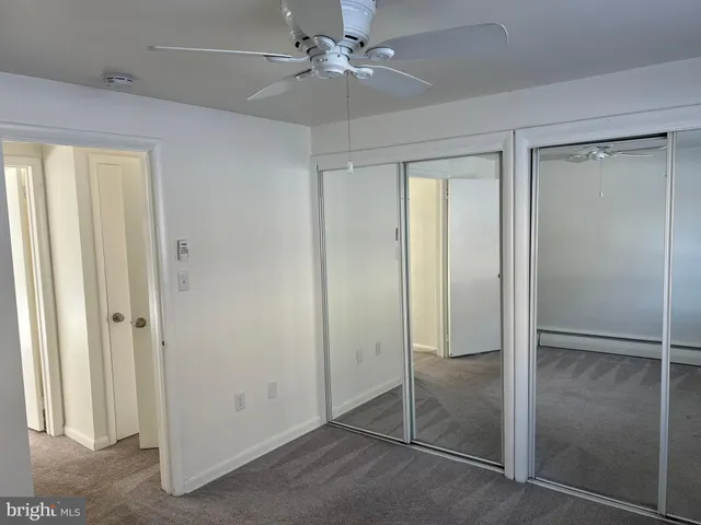 an empty room with closet and a ceiling fan