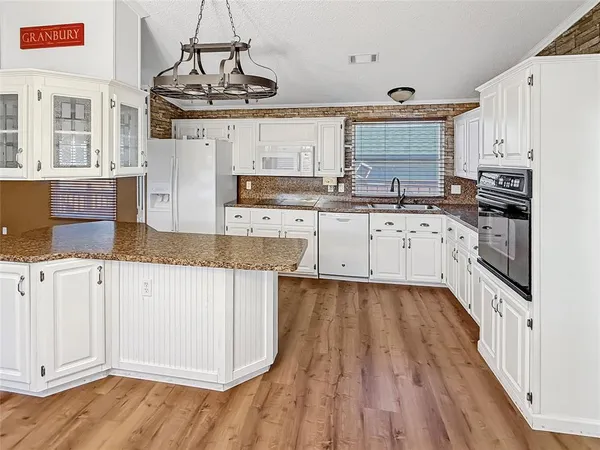 a kitchen with granite countertop white cabinets white appliances and granite counter tops