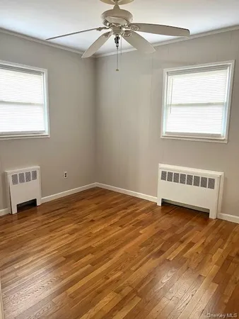 a view of an empty room with a window and wooden floor