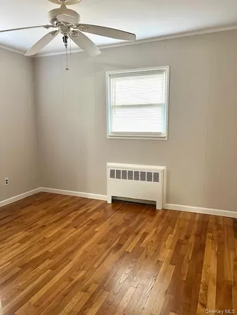 a view of an empty room with a window and wooden floor