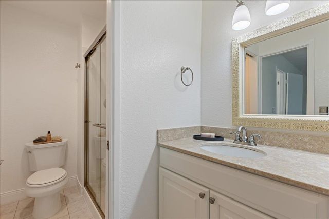 a bathroom with a granite countertop toilet sink and mirror