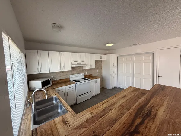 a kitchen with a sink dishwasher stove and white cabinets