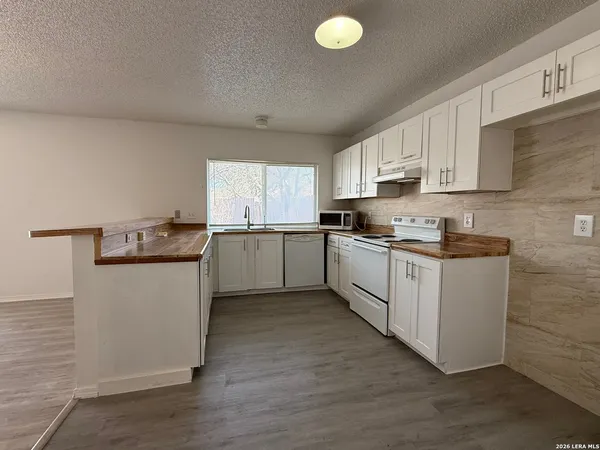 a kitchen with granite countertop white cabinets and white appliances