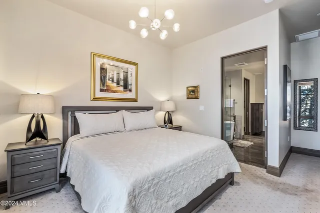 a spacious bedroom with a large bed and a chandelier