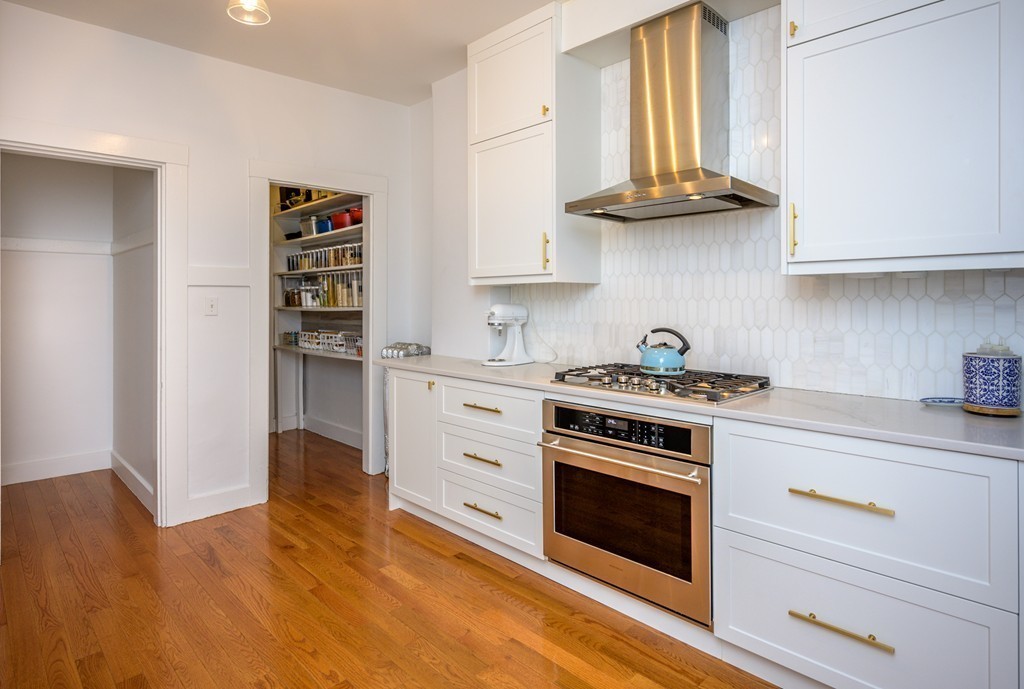 36 Stanton Road, Unit 1 Brookline, MA 02445 - Photo 5 of 17 a kitchen with stainless steel appliances a stove a sink and a refrigerator with wooden floors