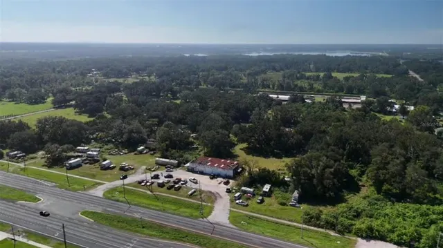 an aerial view of a residential houses with outdoor space and trees