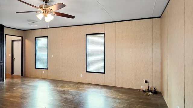 an empty room with wooden floor chandelier fan and windows