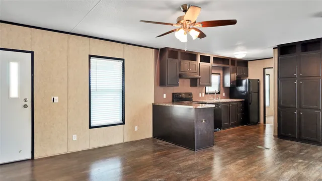a kitchen with kitchen island a counter top space appliances and a ceiling fan