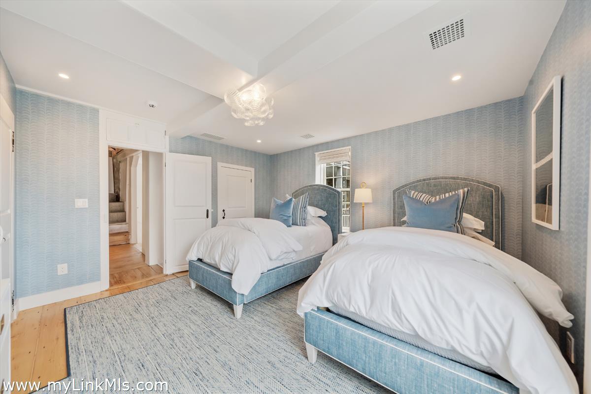 10 North Water Street Nantucket, MA 02554 - Photo 53 of 78 a spacious bedroom with two beds and a chandelier