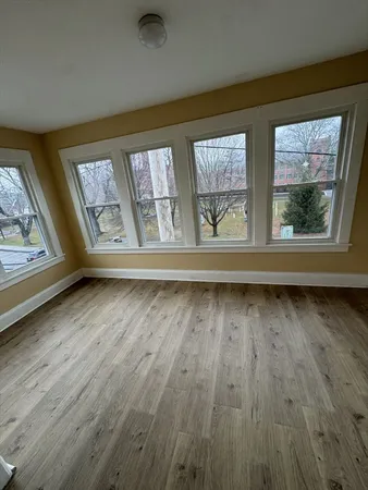 a view of an empty room with wooden floor and a window