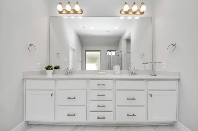 a spacious bathroom with a double vanity sink a mirror a vanity and a bathtub