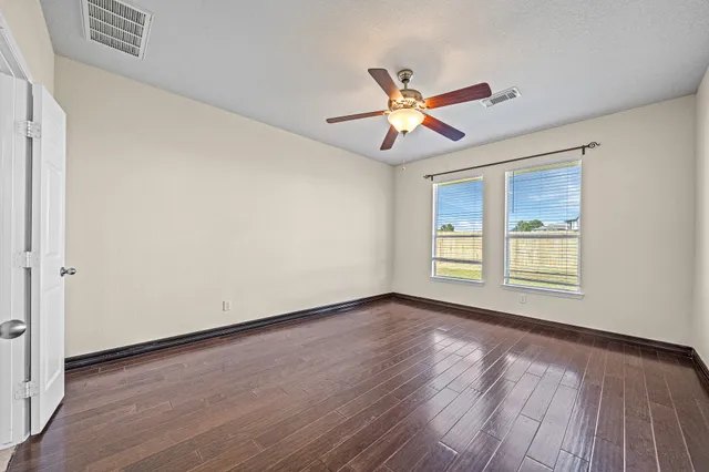 a view of an empty room with wooden floor and a window
