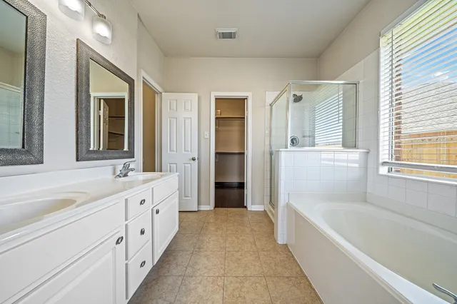 a spacious bathroom with a tub sink and mirror