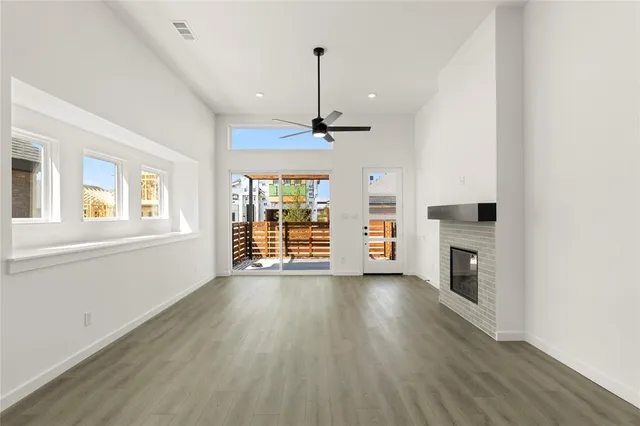 an empty room with wooden floor fireplace and windows
