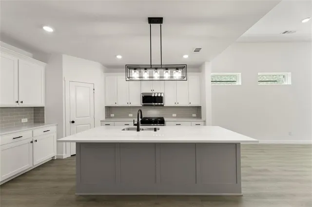 a large kitchen with kitchen island a sink stainless steel appliances and cabinets