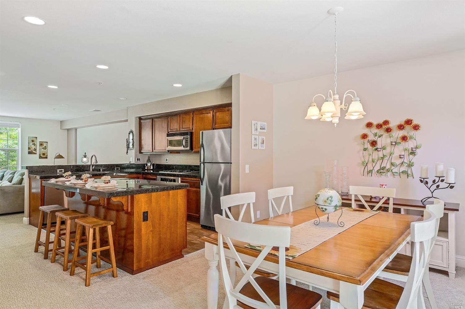 a kitchen with stainless steel appliances a table and chairs in it