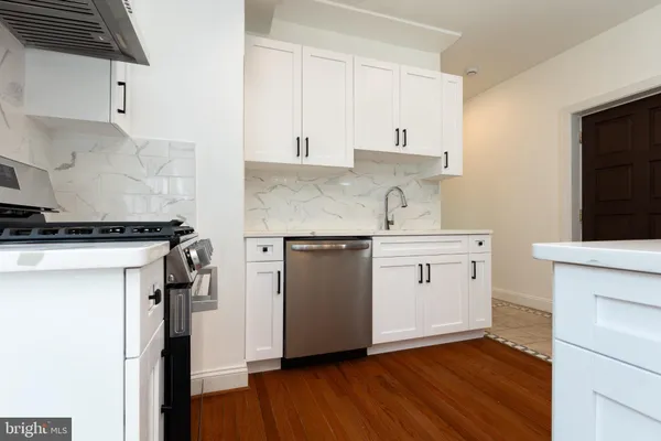 a kitchen with a white cabinets and wooden floor