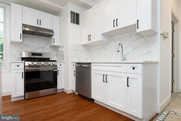 a kitchen with cabinets stainless steel appliances and wooden floor