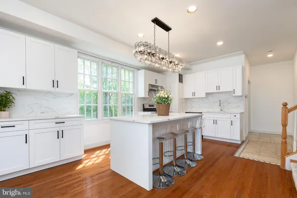 a kitchen with stainless steel appliances granite countertop a white cabinets stove a sink and dishwasher with wooden floor