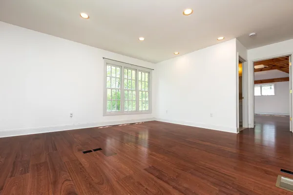 an empty room with wooden floor and windows