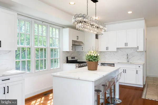 a kitchen with stainless steel appliances granite countertop a kitchen island hardwood floor sink stove and white cabinets