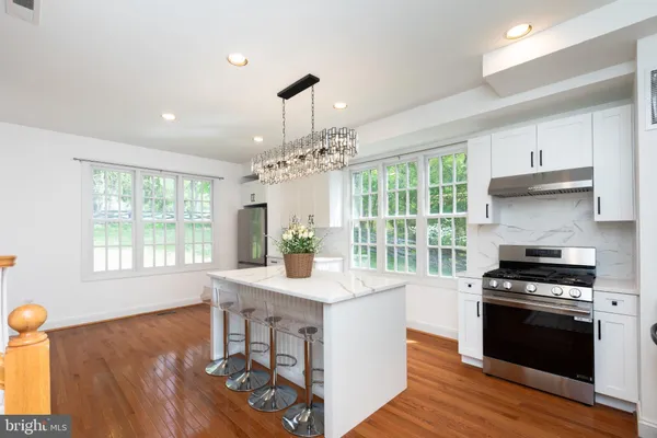 a kitchen with stainless steel appliances granite countertop a stove and a wooden floor