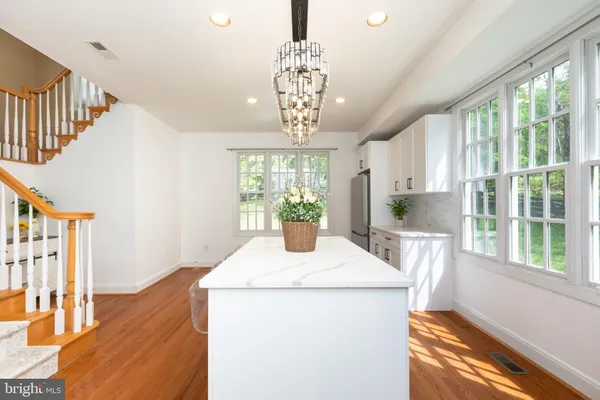 a dining room with wooden floor a chandelier a wooden table and chairs