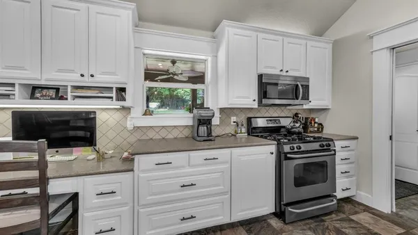 a kitchen with white cabinets and appliances