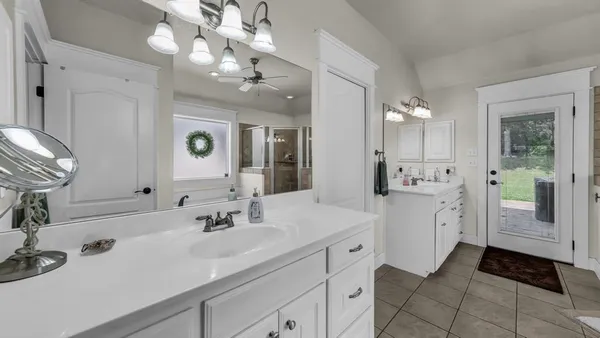 a spacious bathroom with a double vanity sink a mirror and a shower