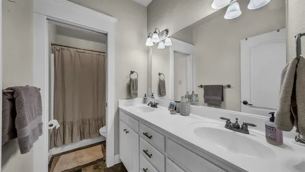 a bathroom with double vanity sinks a vanity a lamp and a mirror