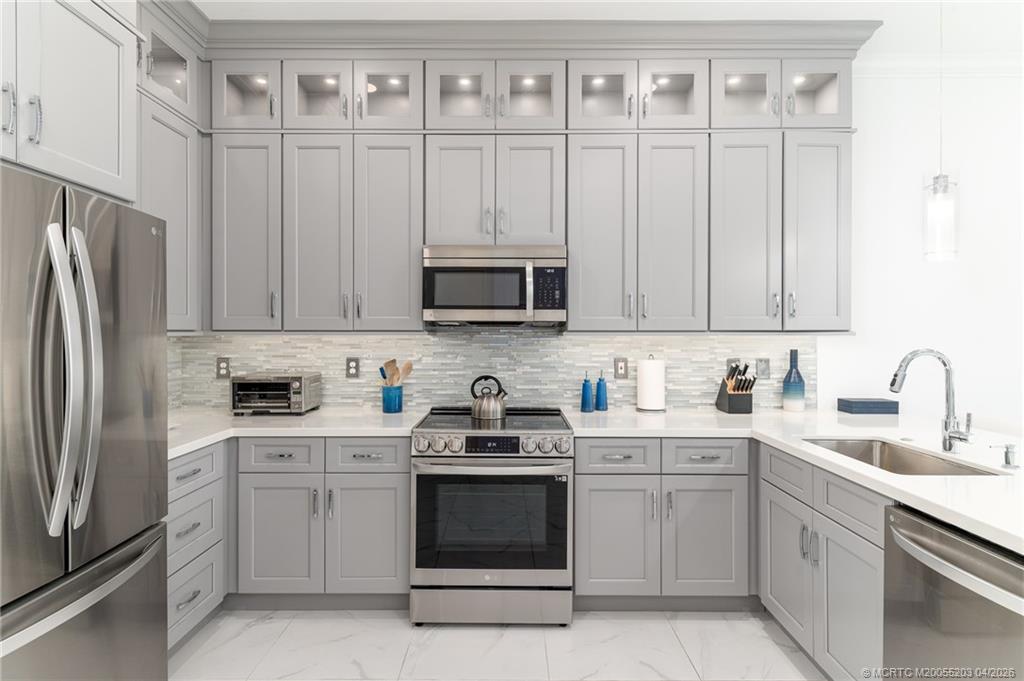 4683 Southeast Manatee Terrace Stuart, FL 34997 - Photo 22 of 45 a kitchen with white cabinets stainless steel appliances and sink