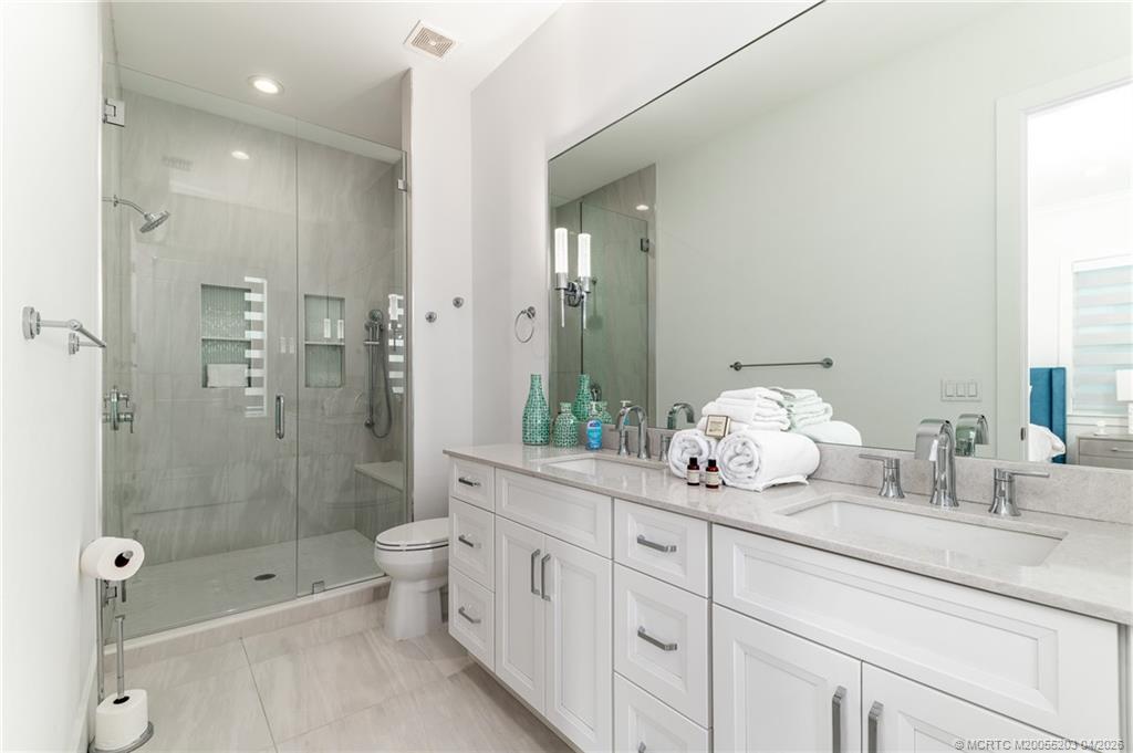 4683 Southeast Manatee Terrace Stuart, FL 34997 - Photo 27 of 45 a bathroom with a double vanity sink toilet and shower