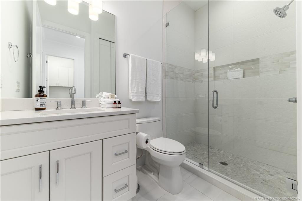 4683 Southeast Manatee Terrace Stuart, FL 34997 - Photo 34 of 45 a bathroom with a shower sink mirror and a toilet