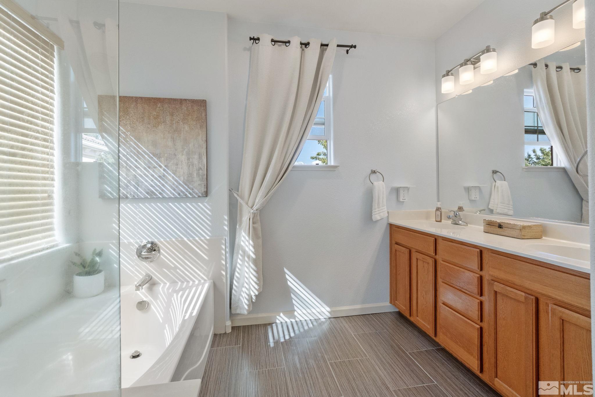420 Stradella Court Reno, NV 89521 - Photo 23 of 40 a bathroom with a double vanity sink a mirror and a bathtub