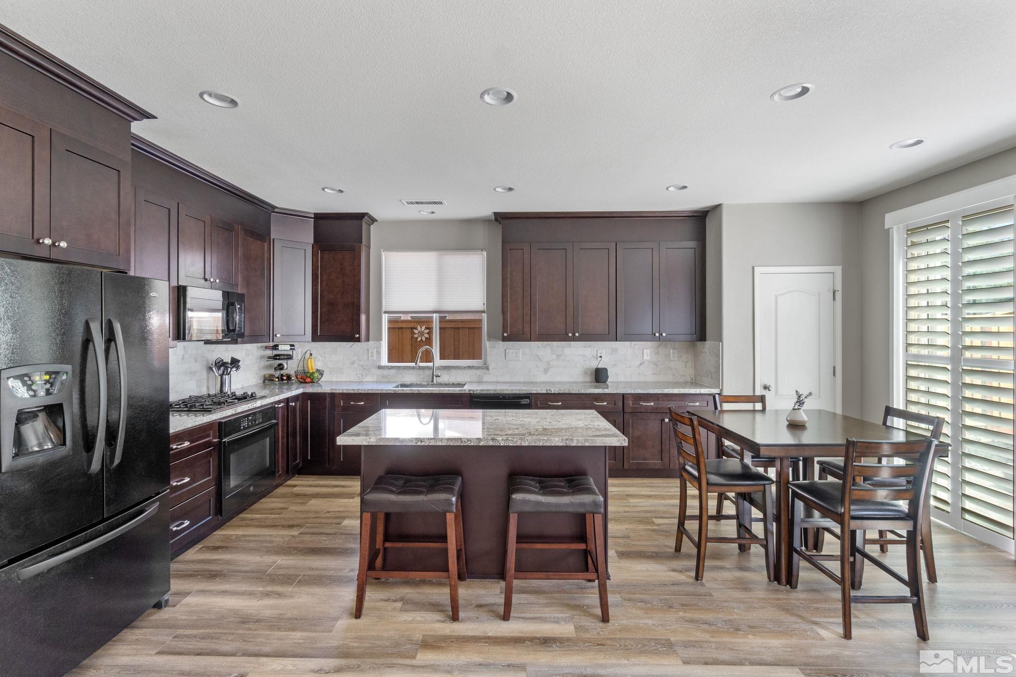 420 Stradella Court Reno, NV 89521 - Photo 5 of 40 a kitchen with granite countertop a dining table chairs and refrigerator