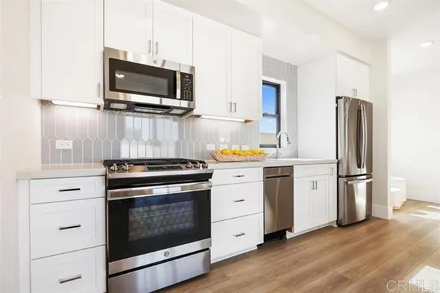 a kitchen with white cabinets and stainless steel appliances