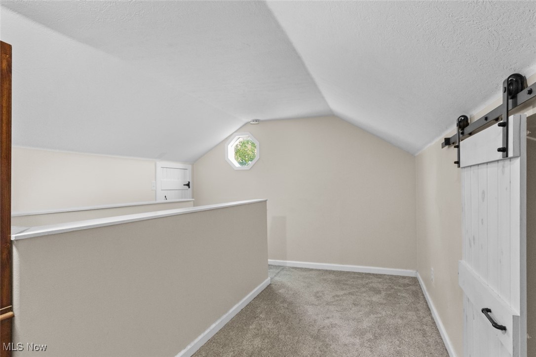 1824 Amherst Road Northeast Massillon, OH 44646 - Photo 26 of 34 Bedroom with a textured ceiling, lofted ceiling, light carpet, and a barn door