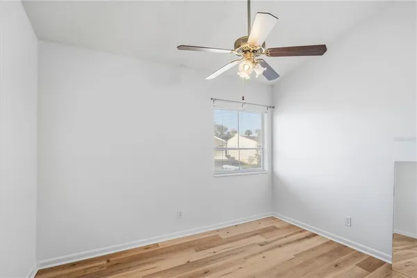 an empty room with wooden floor fan and windows