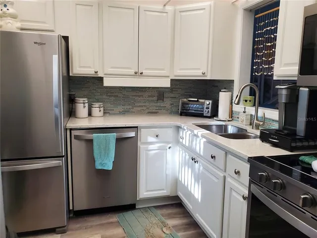 a kitchen with stainless steel appliances granite countertop a refrigerator a stove and a sink