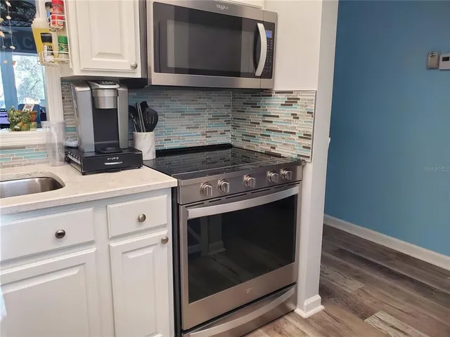 a kitchen with granite countertop white cabinets stainless steel appliances and sink