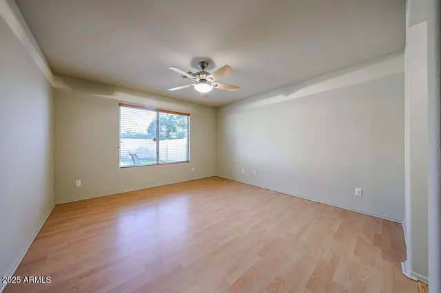 an empty room with wooden floor chandelier fan and windows