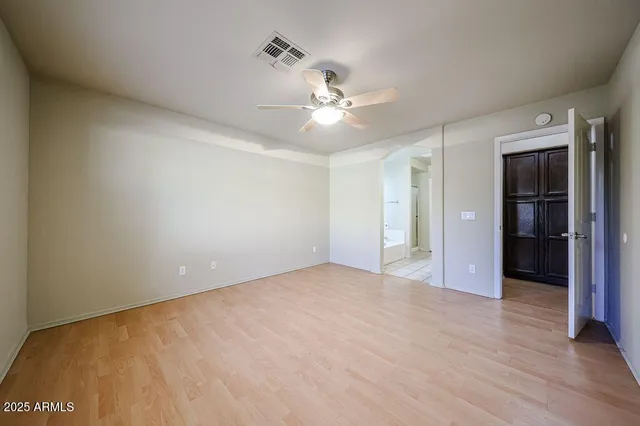 an empty room with closet and a ceiling fan