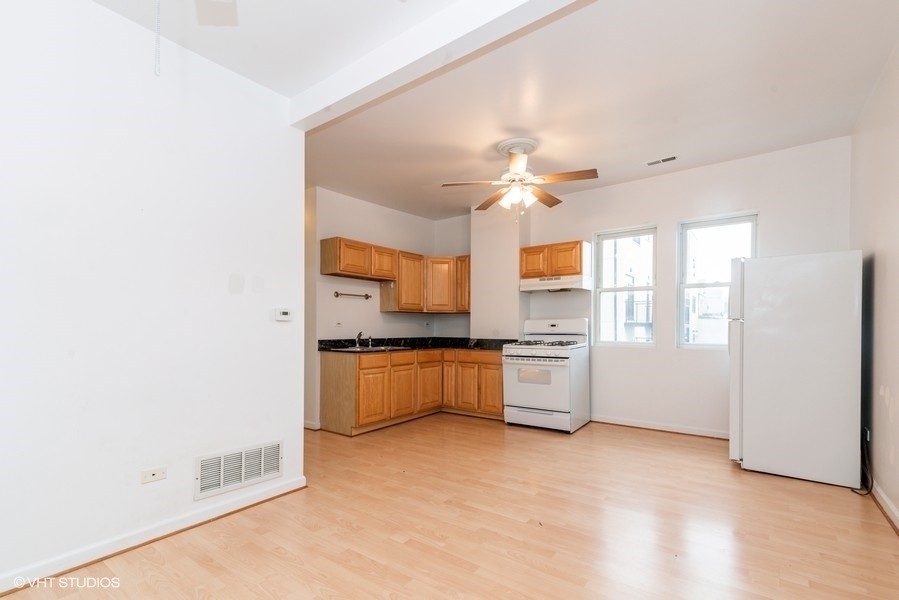 912 North Ashland Avenue, Unit 3C Chicago, IL 60622 - Photo 2 of 7 a large white kitchen with a sink stainless steel appliances and a window