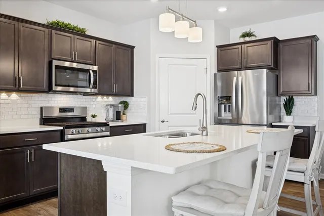 a kitchen with kitchen island granite countertop a sink cabinets and stainless steel appliances