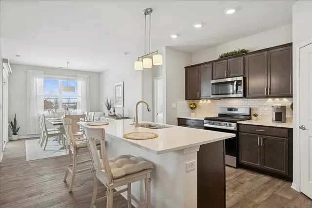 a kitchen with stainless steel appliances granite countertop a stove a sink a microwave a stove a dining table and chairs